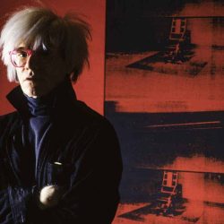 8_Alberto Venzago_Andy Warhol posiert vor dem Bild Little Electric Chair_1964 1965_Factory_Union Square West_New York_1984_copyright Alberto Venzago