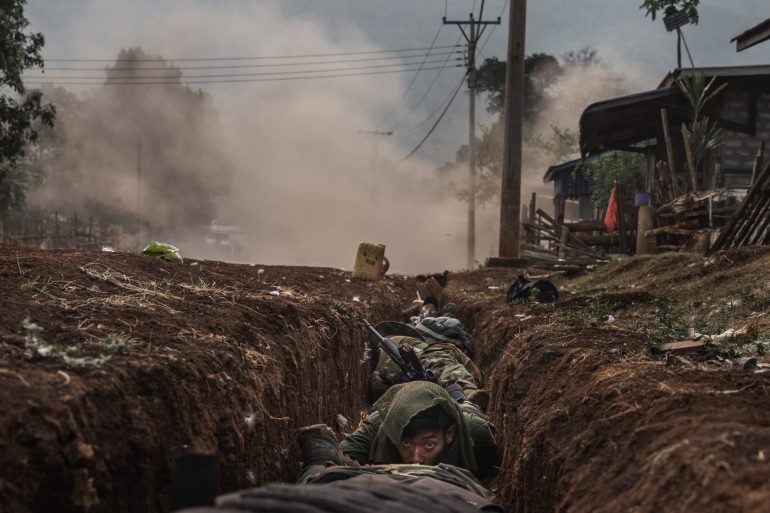 Karenni soldiers take shelter on a roadside drainage ditch as a mortar shell explodes close by